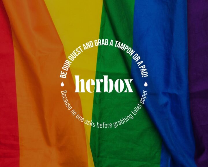 Prideflagga med texten "herbox: Be our guest and grab a tampon or a pad! Because no one asks before grabbing toilet paper"