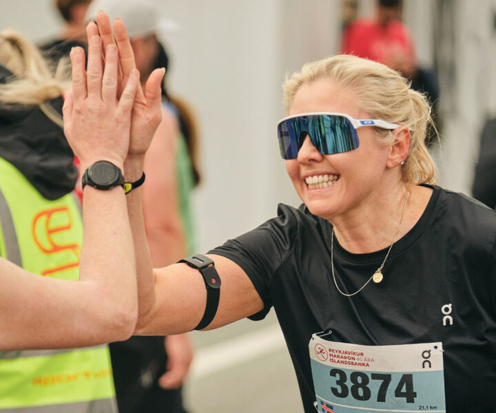 Kvinna med solglasögon gör en high-five efter målgång i Reykjavik Marathon