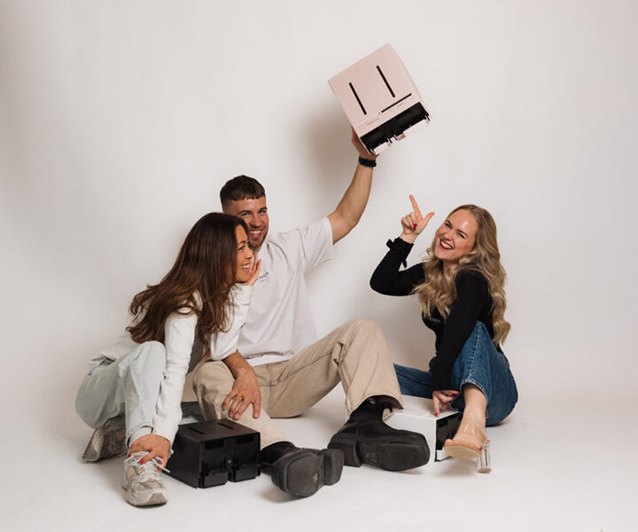 Het Herbox-team zit op de grond met dispensers in verschillende kleuren, een uiting van eenheid en vreugde