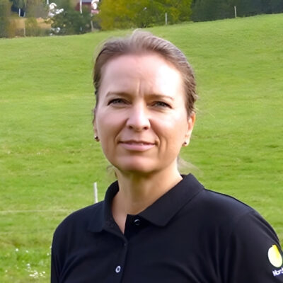 Sara Marklund platschef på Nordvik Utbildningar i svart tröja står på en grön äng med träd i bakgrunden.
