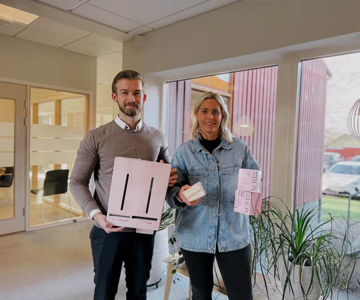 Foto van twee Sparbanken-medewerkers: een jonge man met een roze Herbox-dispenser en een jonge vrouw met tampons en maandverband