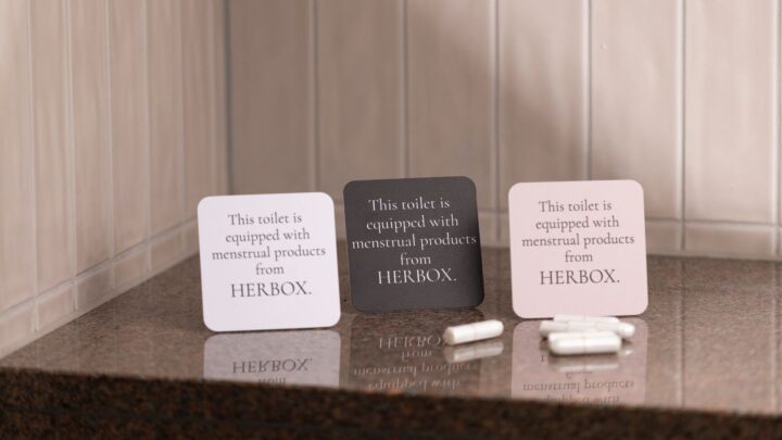 Skylt som visar att toaletten erbjuder mensskydd från Herbox på arbetsplatsen