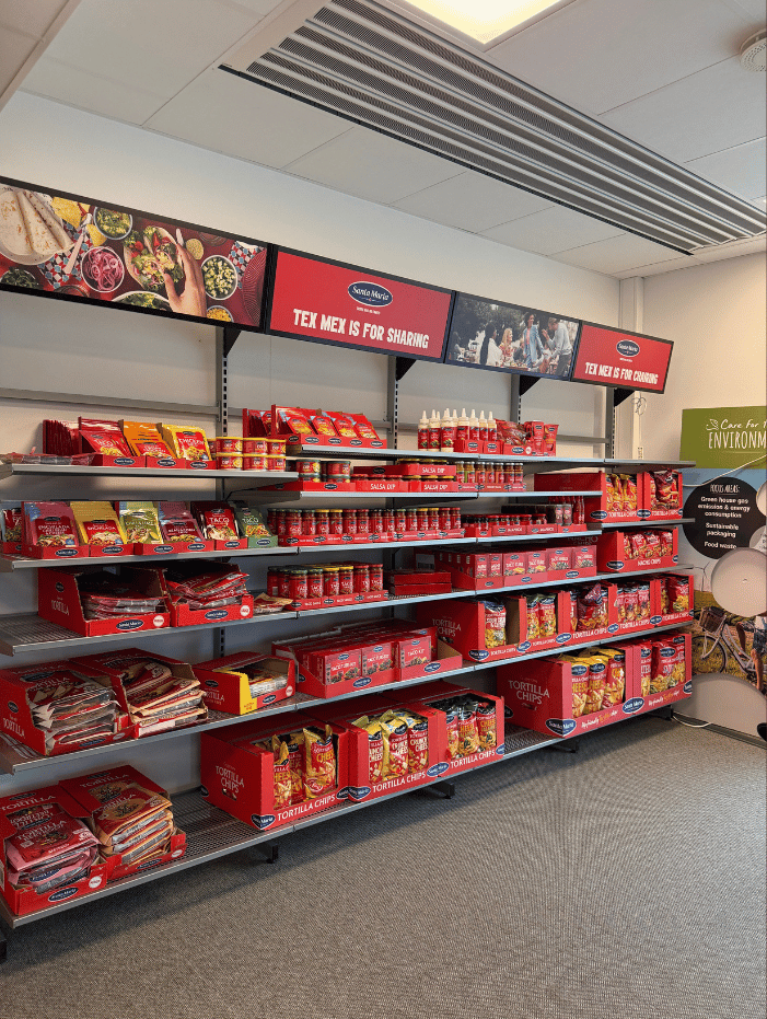 Hylla i mataffär med Santa Maria Tex Mex-produkter som tortilla chips, salsa och kryddmixer i röda förpackningar.