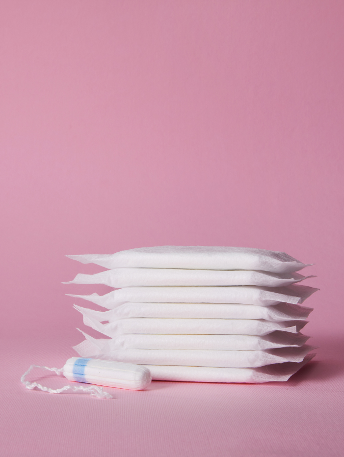 En tampong och en stapel bindor på rosa bakgrund.